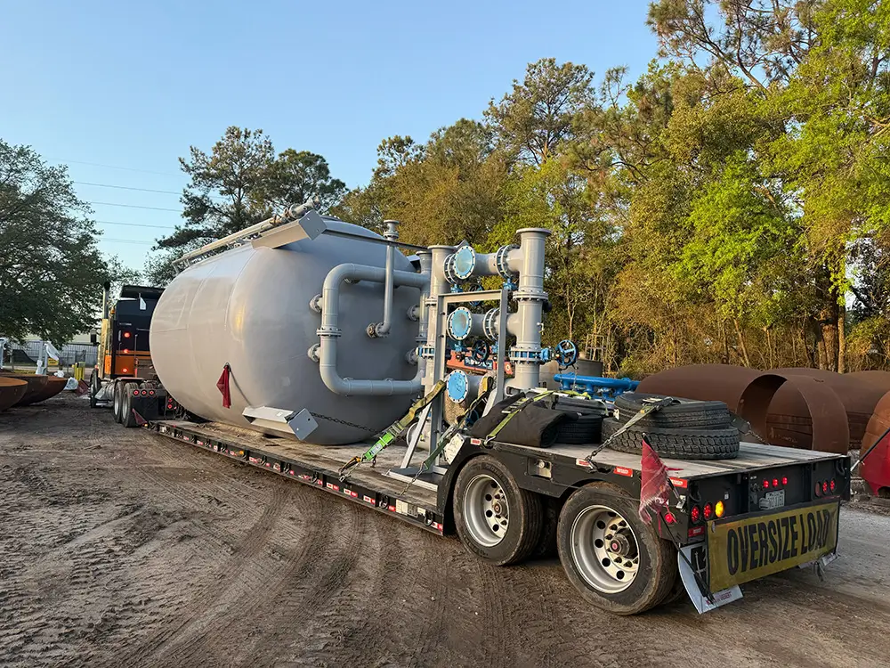 Industrial pressure vessel with piping and valves loaded on a Tavus Transportation lowboy trailer